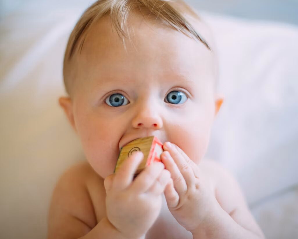 Een baby onderzoekt een houten speelgoedblokje