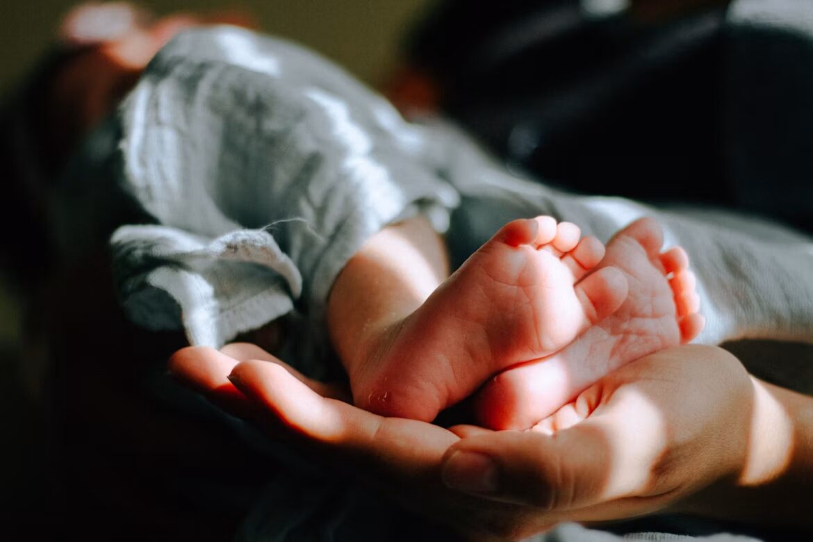 Een volwassen hand houdt een babyhandje vast