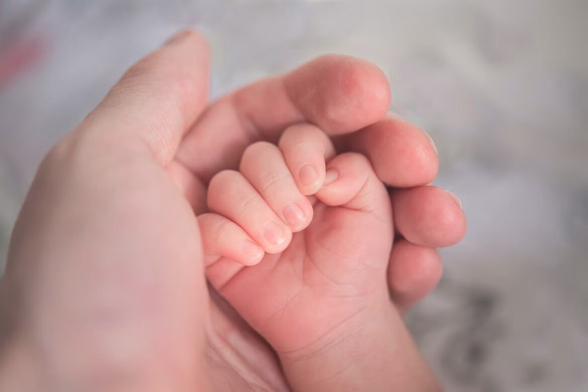 Een ouder houdt de blote voetjes van een baby vast